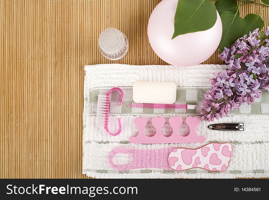 On the wooden table flowers, cream, soap, a brush for cleaning the face and pink pedicure set. On the wooden table flowers, cream, soap, a brush for cleaning the face and pink pedicure set
