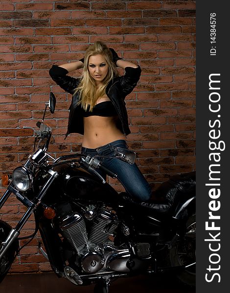 girl sitting on a motorcycle inside a studio with brick background. girl sitting on a motorcycle inside a studio with brick background