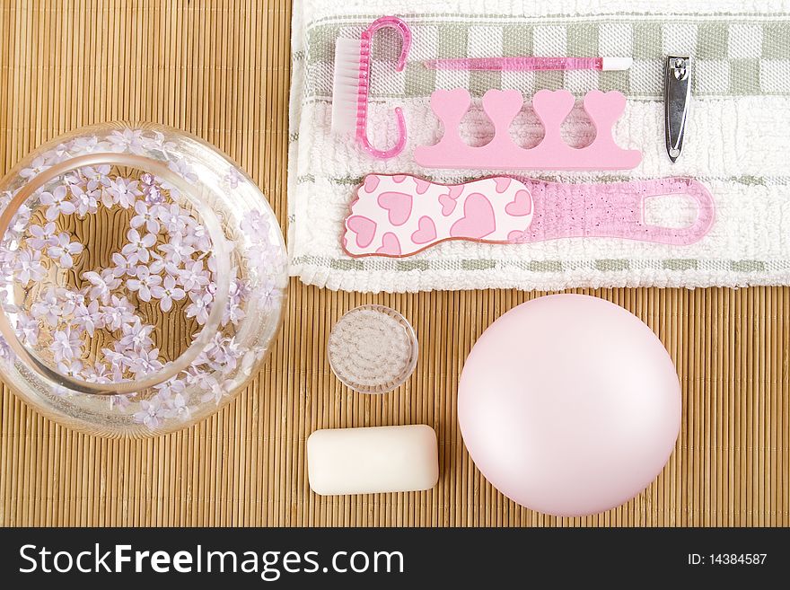 On the wooden table flowers, cream, soap, a brush for cleaning the face and pink pedicure set. On the wooden table flowers, cream, soap, a brush for cleaning the face and pink pedicure set