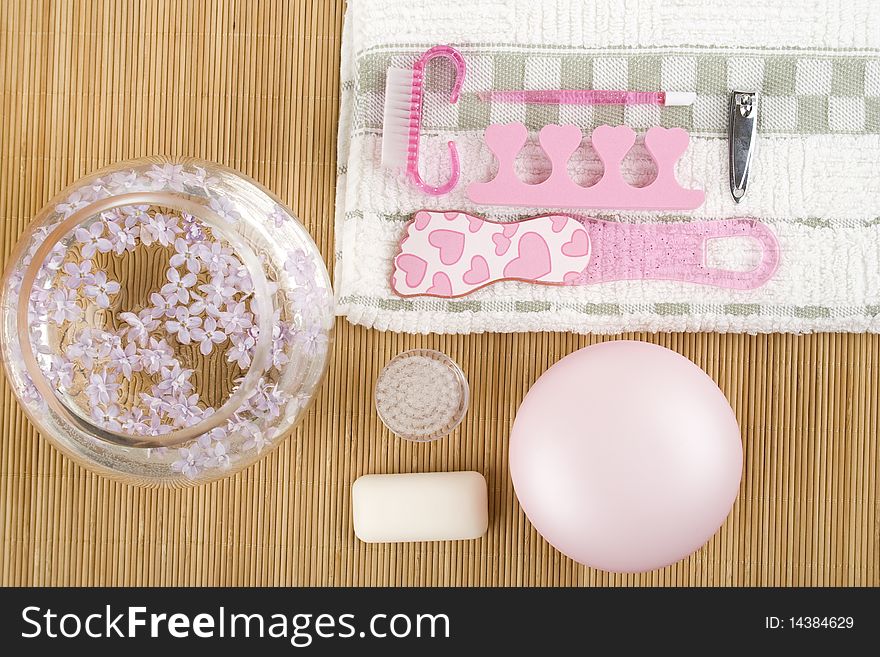 On the wooden table flowers, cream, soap, a brush for cleaning the face and pink pedicure set. On the wooden table flowers, cream, soap, a brush for cleaning the face and pink pedicure set