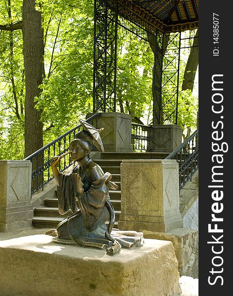 A bronze statue depicting a Chinese woman with an umbrella and a fan near the bridge in the Chinese style