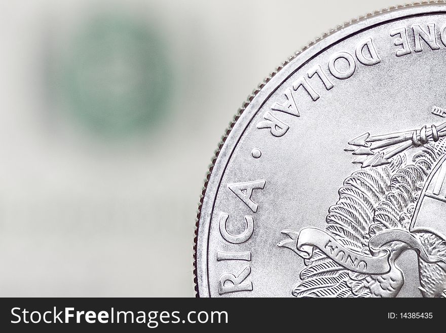 Silver shiny one dollar coin on a blurry background of dollar bill. Silver shiny one dollar coin on a blurry background of dollar bill