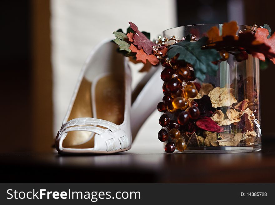 White wedding woman shoes on a table near decorative glass. White wedding woman shoes on a table near decorative glass.