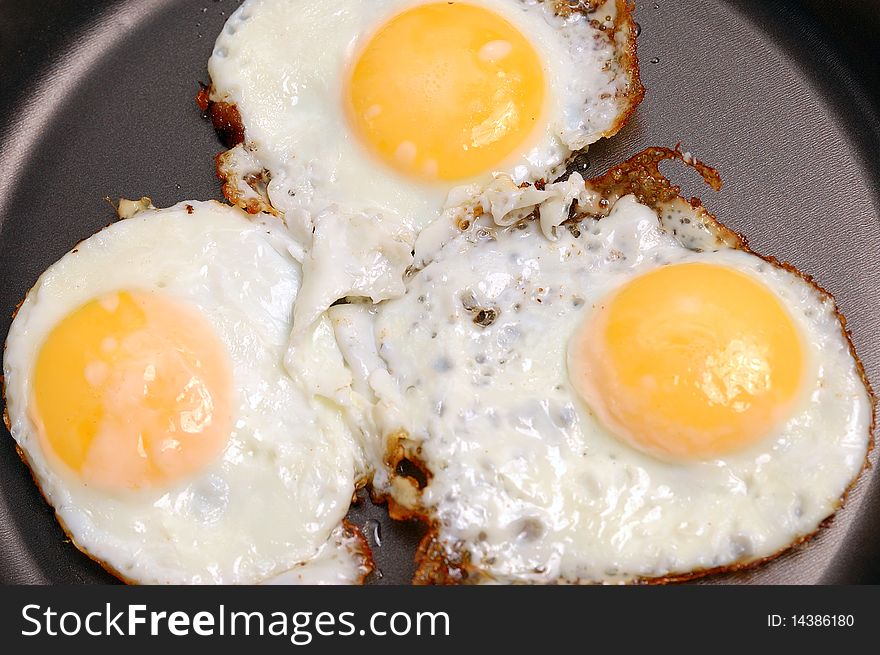 The frying pan with fried eggs. Background of three eggs