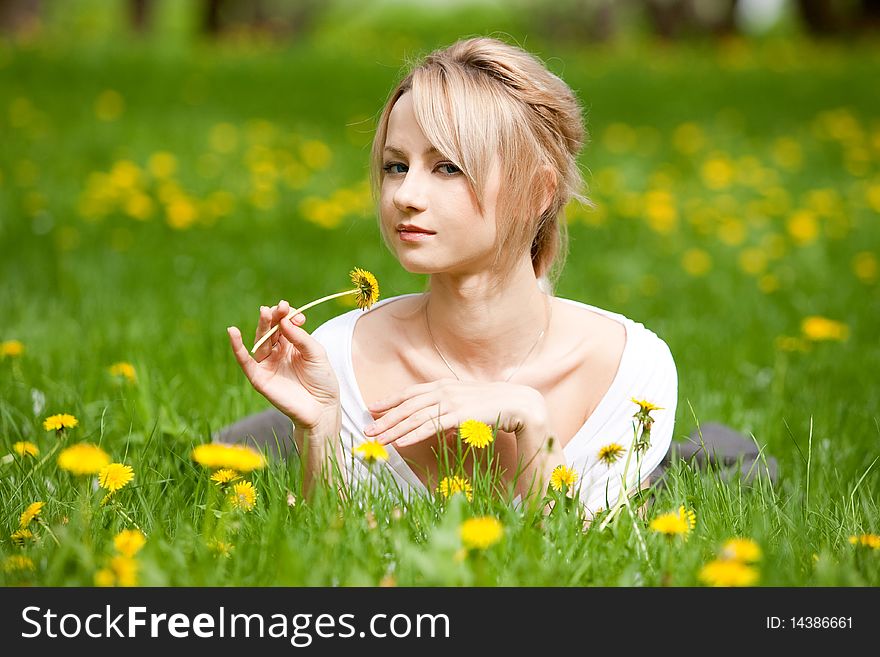 Blonde girl in dandelions, outdoors