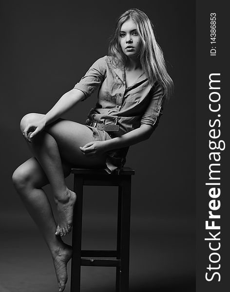Black and white shot of girl sits on chair with naked legs