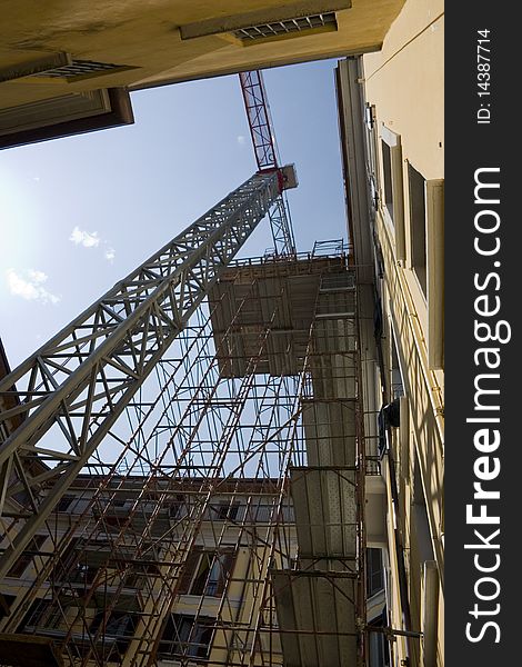 Crane and construction scaffold near a building under restructuring. Crane and construction scaffold near a building under restructuring