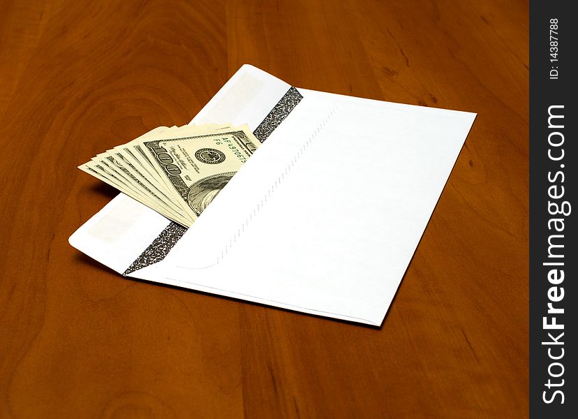 Dollar bills in a white envelope on the office desk. Dollar bills in a white envelope on the office desk.