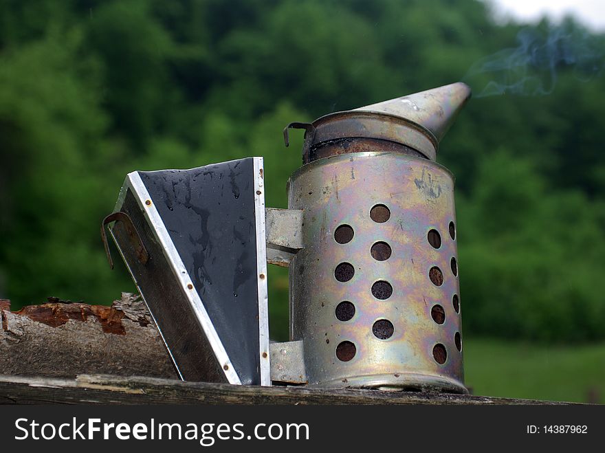 Beekeeper's smoker with smoke, piece of wood