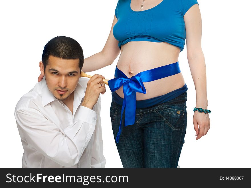 Pregnant girl with blue ribbon on her abdomen and her husband listening in their baby. Pregnant girl with blue ribbon on her abdomen and her husband listening in their baby.
