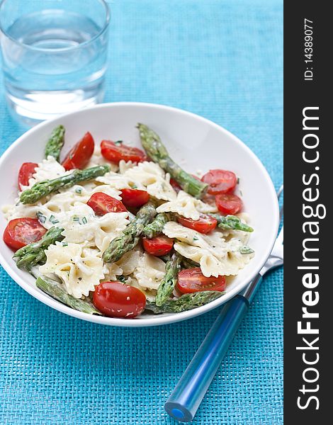 Dinner set with farfalle asparagus salad on a blue background. Dinner set with farfalle asparagus salad on a blue background