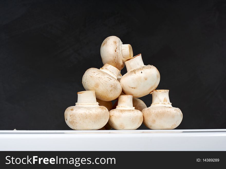 Fresh mushrooms on a white table against the wall