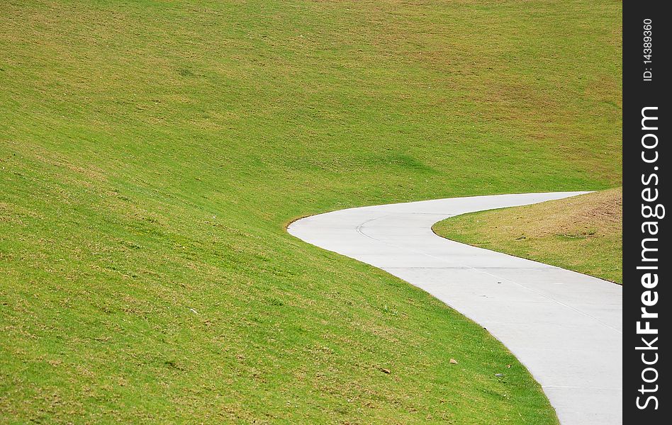 Concrete walkway under green grass hill. Concrete walkway under green grass hill