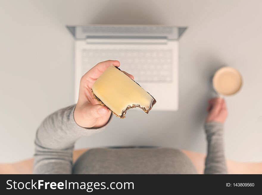 Woman having lunch break at workplace with coffee and cheese sandwich.