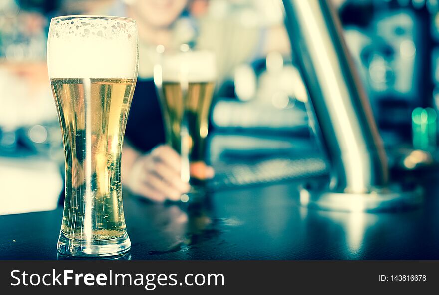 Glass Of Beer On Bar Counter Against Background Of Friendly Bartender