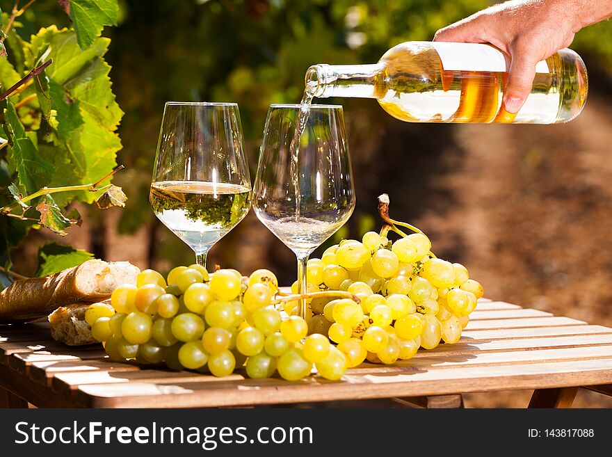 Glass of dry White wine ripe grapes and bread on table in vineyard