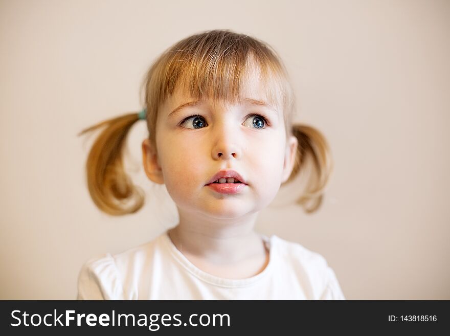 Cute child girl with two pigtails and quiff of blonde hair closeup portrait