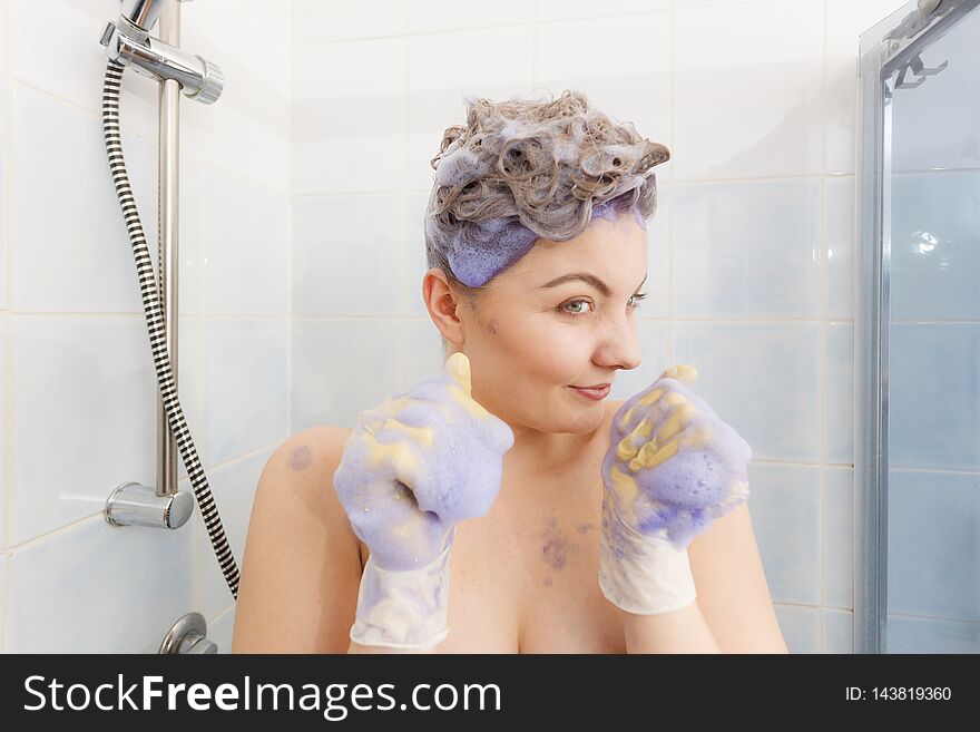 Woman applying coloring shampoo on her hair. Female having purple washing product. Toning blonde color at home. Woman applying coloring shampoo on her hair. Female having purple washing product. Toning blonde color at home