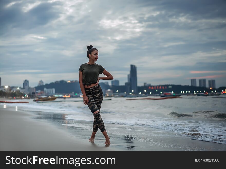 A young girl enjoys a walk on the ocean. Evening walk on a deserted city beach. Evening Pattaya, Thailand.