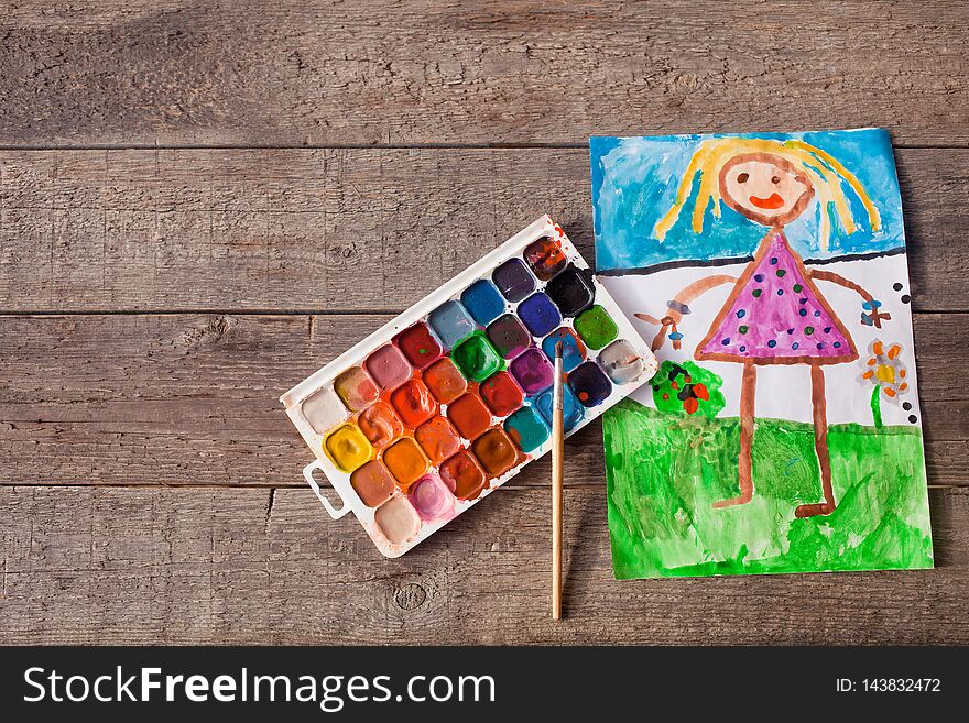 The children is drawing paints on a wooden background