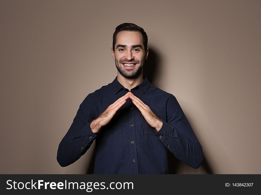 Man showing HOUSE gesture in sign language on color background