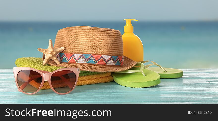 Different beach accessories on table against sea