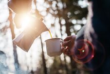 Outdoor Shot Of Young Woman Pours Itself Hot Beverage In Mountains Near To Bonfire During The Sunset. Stock Photos