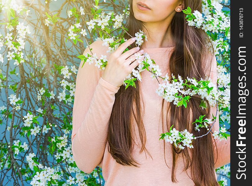 Pretty young brunette woman`s hand touching a blooming tree branches. Fashion, happiness and lifestyle concept. Pretty young brunette woman`s hand touching a blooming tree branches. Fashion, happiness and lifestyle concept.