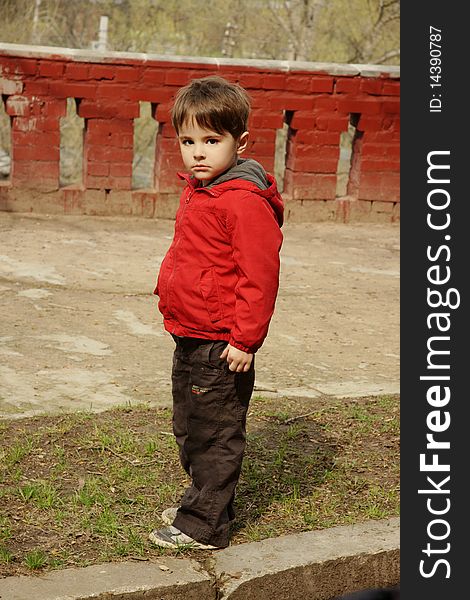 Beautiful little boy in red jacket with serious look, outdoor shot. Beautiful little boy in red jacket with serious look, outdoor shot