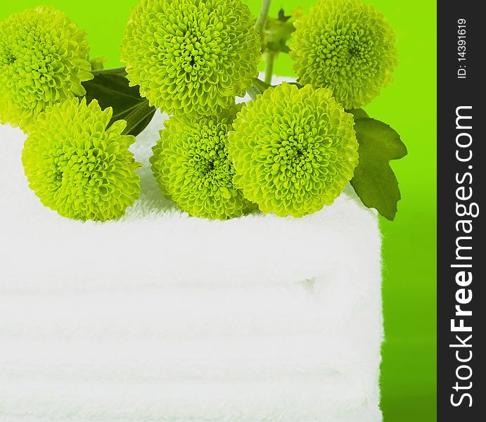 Pile white towels on green background and branch chrysanthemums