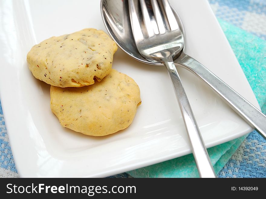 Closeup of nutritious cookies on white plate with utensils. Filled with nuts for a healthy afternoon snack or high tea. Concepts such as food and beverage, diet and nutrition, and healthy lifestyle.