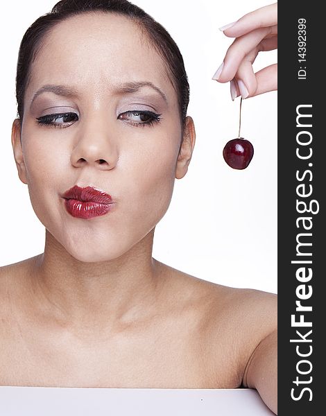 Beauty female face with cherry thinking about to eat .