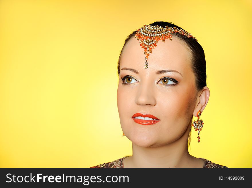 Young beautiful woman in indian traditional jewellary, bindi and sari dress. yellow background. Young beautiful woman in indian traditional jewellary, bindi and sari dress. yellow background