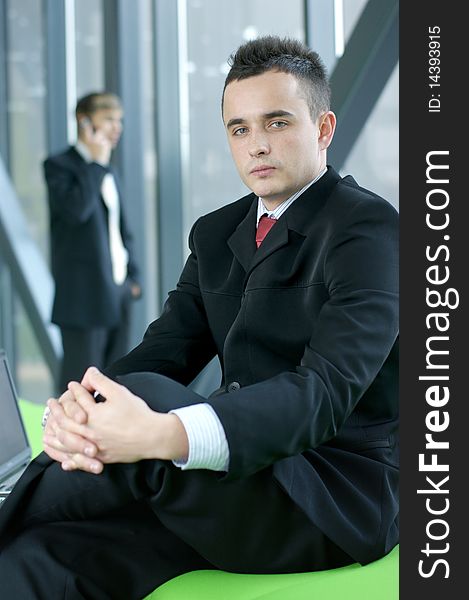 A young business man is sitting in front of his colleague in the office. Image taken on a modern background. A young business man is sitting in front of his colleague in the office. Image taken on a modern background.