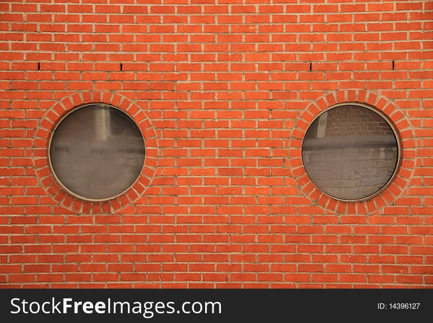 Closeup on round reflective openings in a red brick wall. Closeup on round reflective openings in a red brick wall