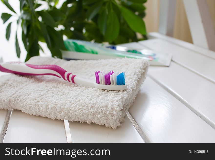 Toothbrush on a white towel, against greens. Toothbrush on a white towel, against greens