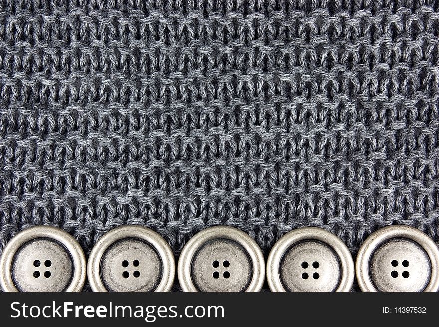 Metal buttons on a gray knitted fabric background. Metal buttons on a gray knitted fabric background