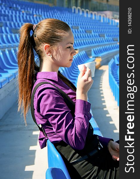 Young businesswoman drinking tea at the stadium