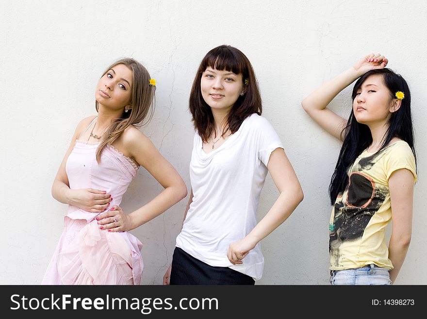 Three female friends standing in front of a white wall
