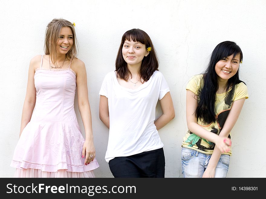 Three female friends standing in front of a white wall