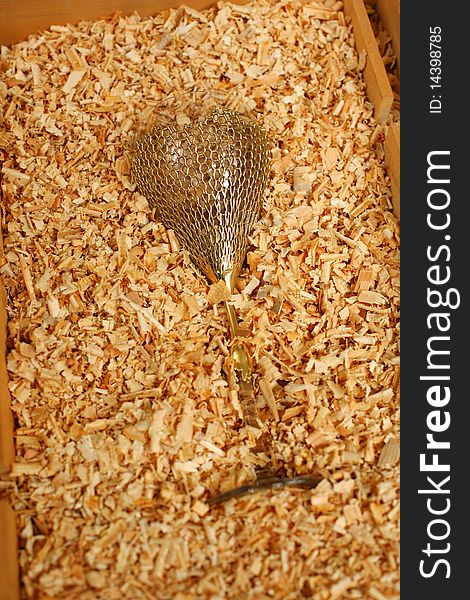 Golden glass in a box with wood chips