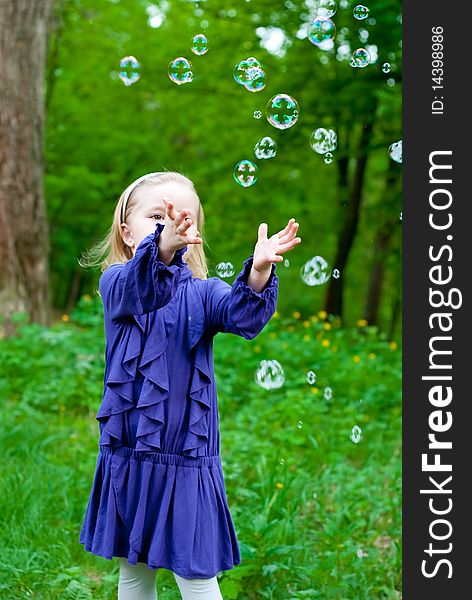 Little girl in park catching bubbles. Outdoor shot. Little girl in park catching bubbles. Outdoor shot