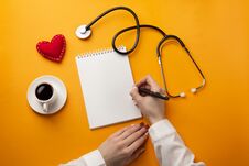 Professional Doctor Writing Medical Records In A Notebook With Stethoscope, Coffee Cup, Syringe And Heart Royalty Free Stock Images