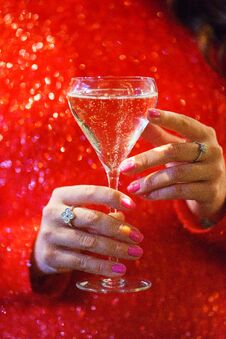 Glass Hand Girl. White Wine In The Glass And Girl In A Sparkling Red Dress Close-up. Royalty Free Stock Image