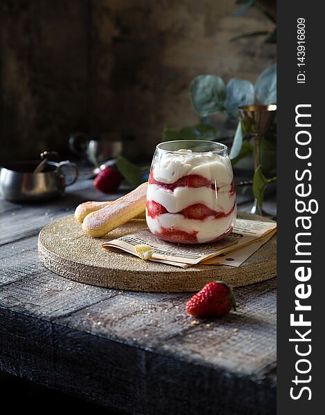 Glass with homemade dessert of whipped cream, red berries, cookies