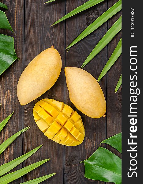 Mango fruit on green leaves, on wooden background. Mango fruit on green leaves, on wooden background.