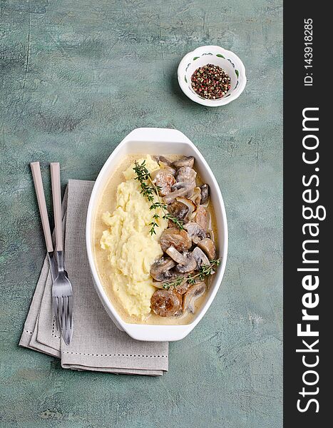 Mashed potatoes and slices of mushrooms with sausages in sauce. Selective focus