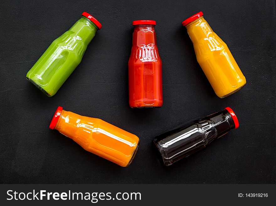 Fresh organic juices in bottles for fitness diet on black background top view mock-up.