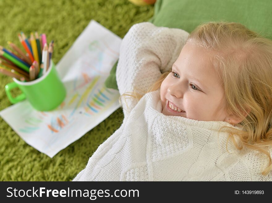 Cute little girl lying on green carpet at home