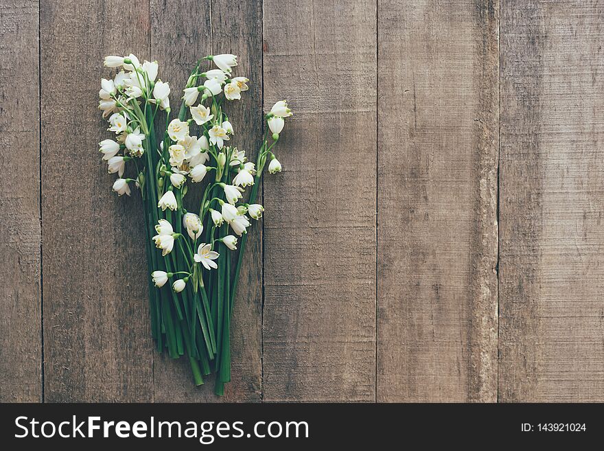 Bouquet of snowdrops primroses on a wooden background. Postcard in a rustic style. Invitation and congratulations on spring holidays